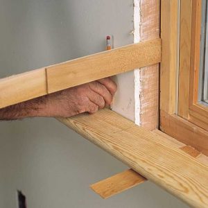 Scribing the stool to the wall. Because the wall is rarely parallel to the stool, this mark, not the edge of the stool, is the baseline for laying out the horn's rip cut.