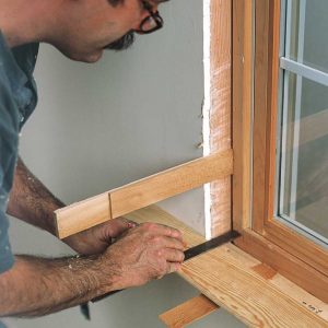 Shims support the stool for layout. The author marks the notch cut on the stool, then measures between it and the window to lay out the rip cut for the horn.