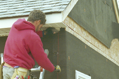 Man on ladder use chalklines to keep corner boards straight