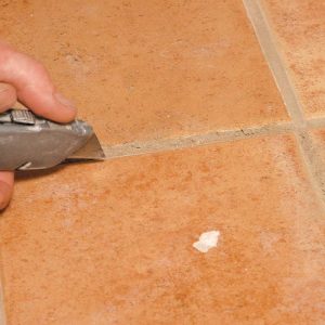 To keep the neighboring tiles intact, the first step is to score the grout lines with a utility knife.