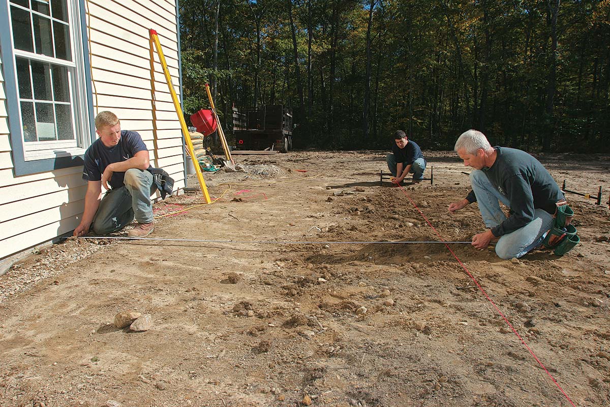 Adjusting the string until it's exactly the right distance from the house foundation.