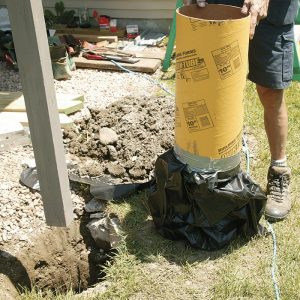 A better footing. After removing the old footings, dig the holes deeper and wider. Based on the footing-size table in DCA-6, footings need to be 16 in. dia. Local code specifies a 40-in. depth. On this job, the author used 12-in.-dia. form tubes with garbage bags taped to the bottom. The bags contain the concrete while permitting it to fill the 16-in.-dia. base entirely at the bottom of the hole. The bags also isolate the concrete from groundwater and soil contamination.