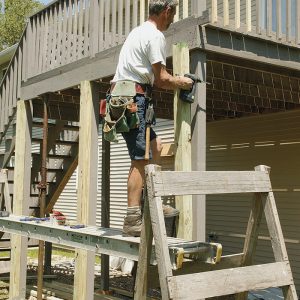 Double the posts. Attach new 4x4 posts to the existing posts with structural screws. The new posts are cut to the height of the rim and rest on galvanized post bases anchored to the new footings 