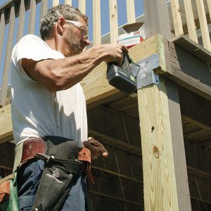 Reinforce the span. The single rim joist spans nearly 6 ft. between posts, far greater than allowed for the deck load. The DCA-6 beam-span table allows a maximum 6-ft. 2-in. span for a double 2x8 southern-yellow pine beam that carries a joist span of 12 ft. After removing the outside decking board, nail a new rim to the existing rim with 16d galvanized nails; then secure each post-rim connection with a galvanized post cap (here, Simpson AC4Z).