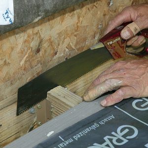 Prepare for framing. Remove the door riser board, the siding, and the first deck board to inspect for rot. After folding up the housewrap, cut a shallow kerf in the joist tops for the flashing edge. 