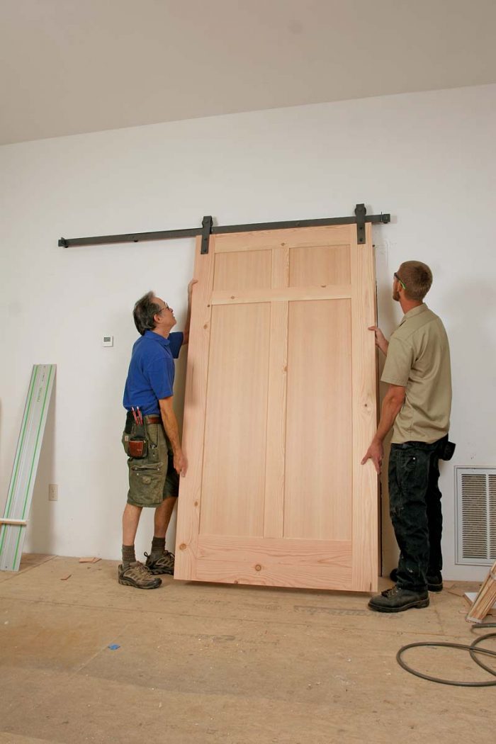 Hang the door. Aided by a helper, put the heavy door on the track.