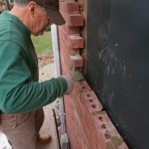 buttering the bed and head joints with mortar on the brick