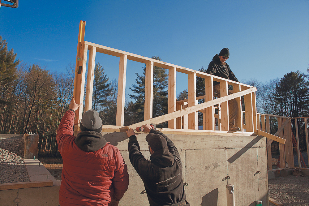 Use a plate level and muscle to plumb the wall sections and corners, and cross-brace with 2x material screwed to the inside of the walls so it doesn’t interfere with sheathing.