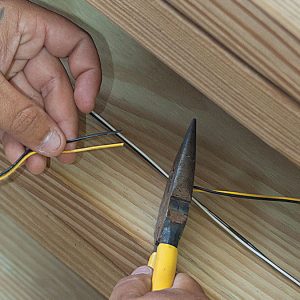 person holding pliers trimming the cable 