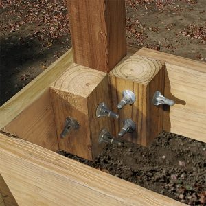 Fasten 4x4 blocks cut the same height as the joists with two ThruLoks in each, driven 2 in. from the top and bottom edges of the framing. Then drive longer ThruLoks through the end and rim joists, post, and blocking.