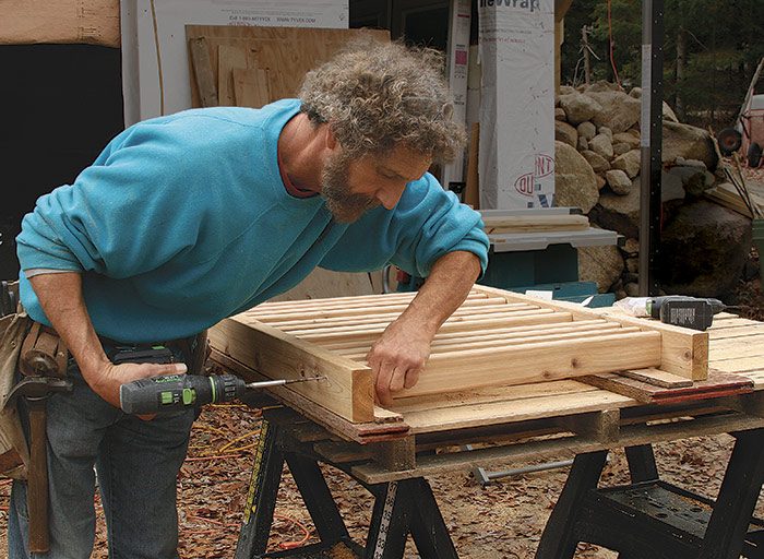 Assembly bench doubles as a jig. Spaced 24 in. apart, strips of 1⁄2-in. plywood raise the 2-1⁄2-in.-deep balusters 1⁄2 in. off the bench, aligning them perfectly on the 2x4 rails. Two 2-1⁄2-in. stainless-steel trim-head screws hold each baluster to each rail.