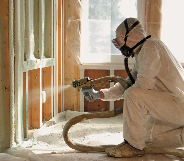 spraying spray foam into wall