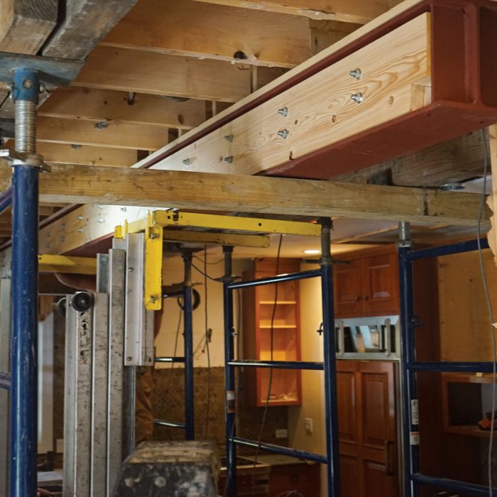 Final positioning. When the beam is close to the ceiling joists, the crew lets it down on timbers spanning between the shoring frames. They then can position it perfectly to slip in between the joists.