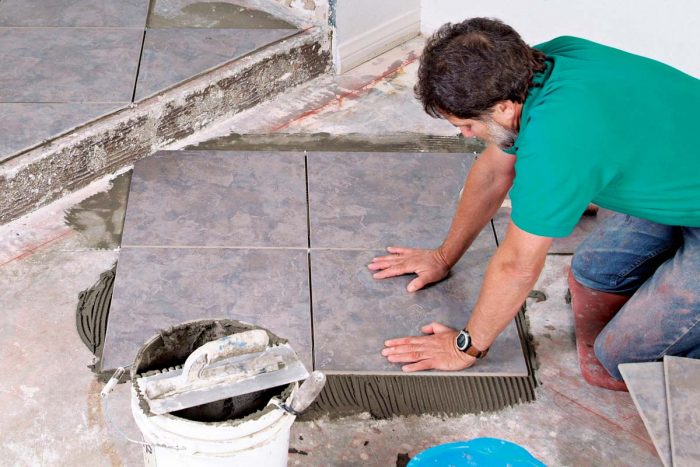 Continue to set full tiles across the floor, using both the edges of the previously set tiles and the chalk layout lines as guides.