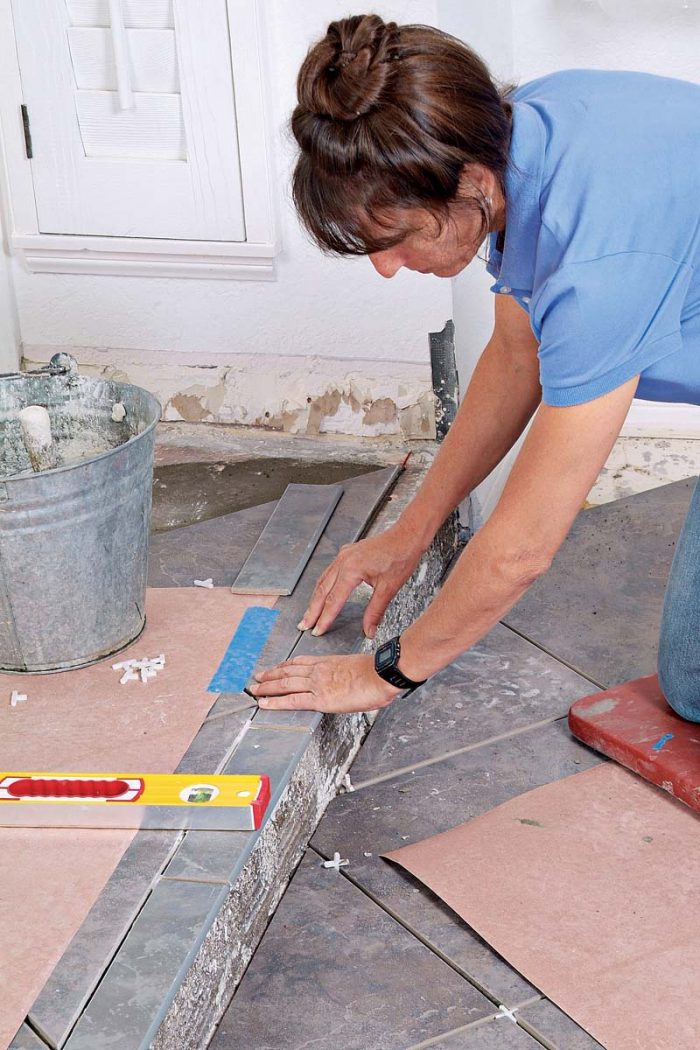 Continue down the edge of the step, setting the bullnose tiles level with one another and adding spacers as you go.