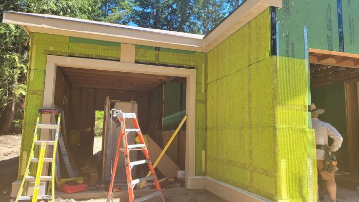 Yellow mesh rainscreen wrapped around the walls of a house