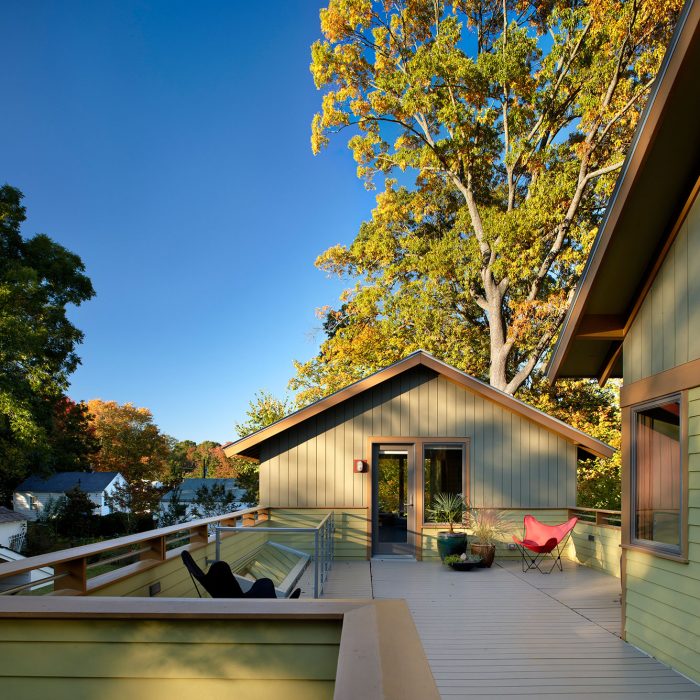 A house and a deck surrounded by green trees