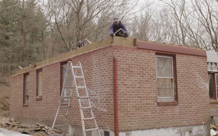 Person workong on second story of brick ranch house