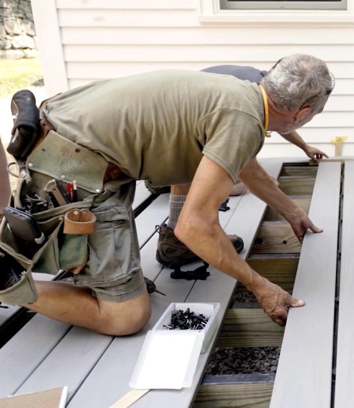 Mike Guertin slides a deck board into place with his assistant Addision.