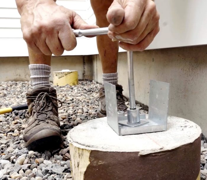 Photo of Mike Guertin's hands anchoring the the post base.