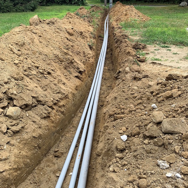 Photo of a trench with electric, cable, and phone lines running through it.