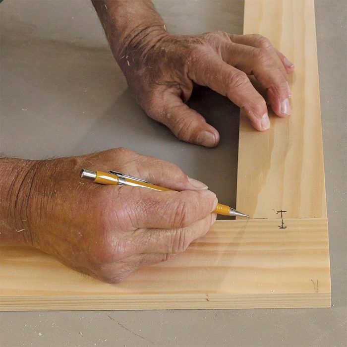 Photo of hands holding a pencil and marking the mortise location on the stile-and-rail connection.