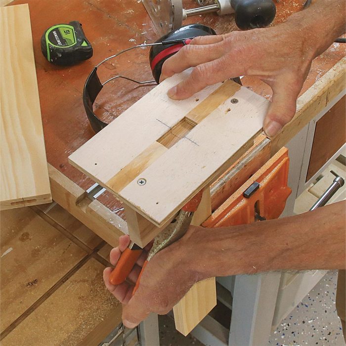 A photo of hands transferring the mark on the center of the mortise to the face of the dry-fit frame to the end of the rail.