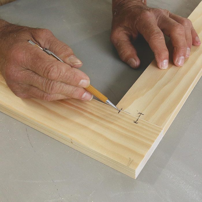 Photo of hands marking the stopped groove on a piece of wood.