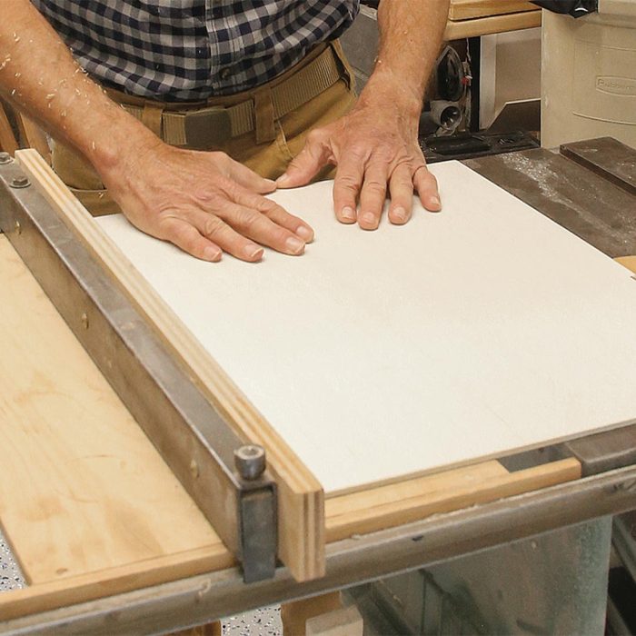 Photo of hands cutting a plywood panel.