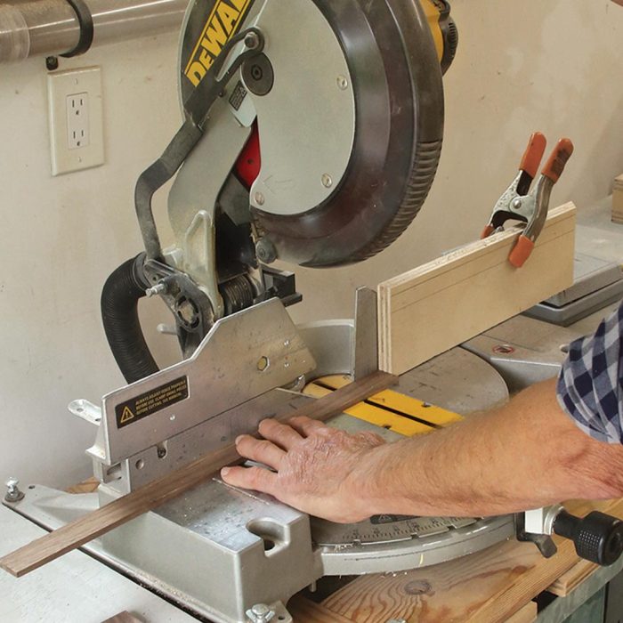 A photo of hands cutting a piece of wood to length.