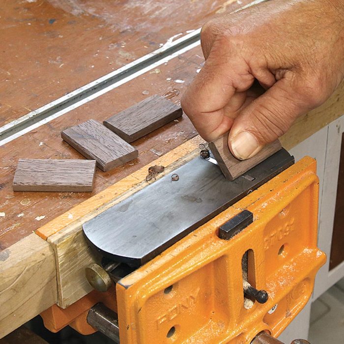 Photo of a hand using a mortise with rounded corners to ease the edges on the tenons.