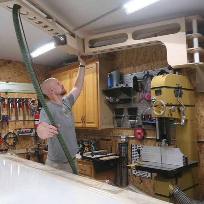 Photo of a man moving a custom arm for tools around the ceiling of his workshop.