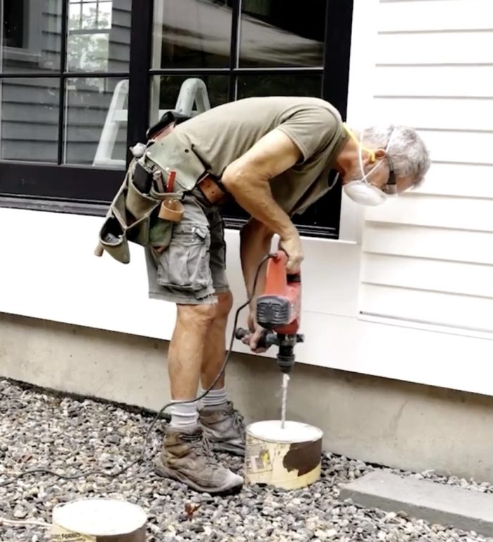 Photo of Mike Guertin drilling into the deck footings.