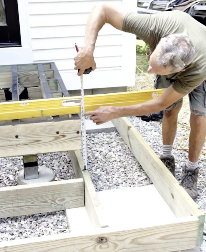 Photo of Mark Guertin measuring for wraparound box-frame stairs on a deck.