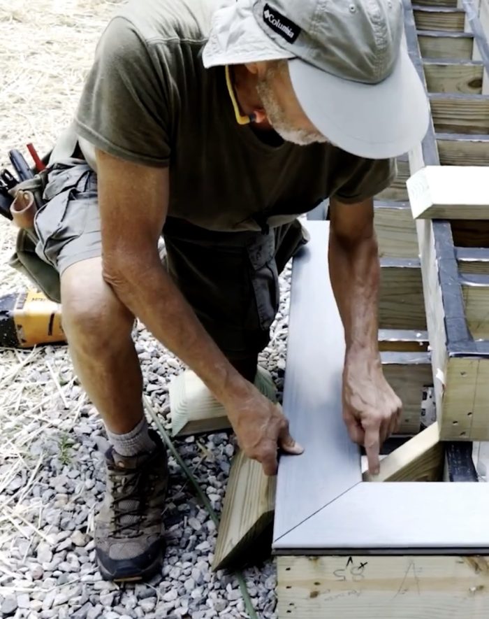 Photo of Mike Guertin showing locations for corner support for wraparound stairs on a deck.