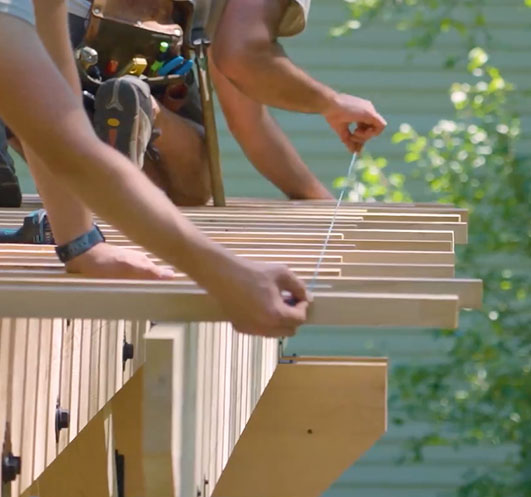 Photo of Jeremy Kassel snapping a chalk line over pergola straps to ensure they're cut evenly.