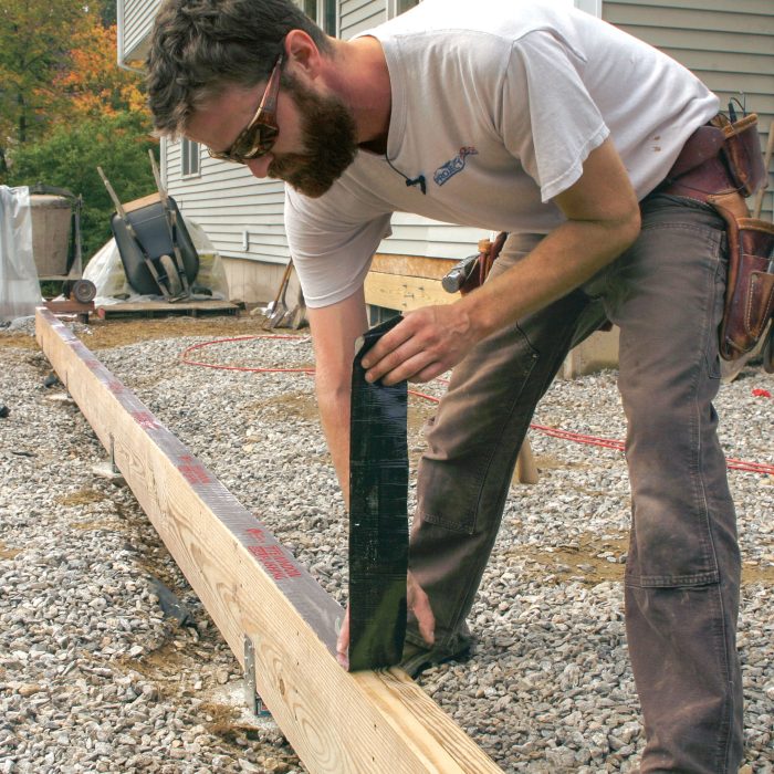 Photo of man covering beam tops with flashing tape to prevent moisture infiltration.