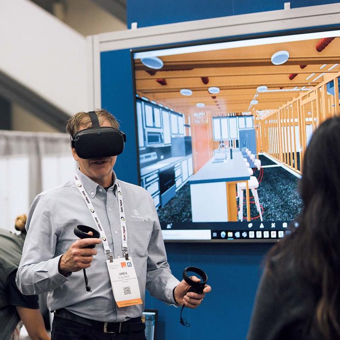 Photo of a man using a virtual reality headset and handset to take a virtual tour of a house.